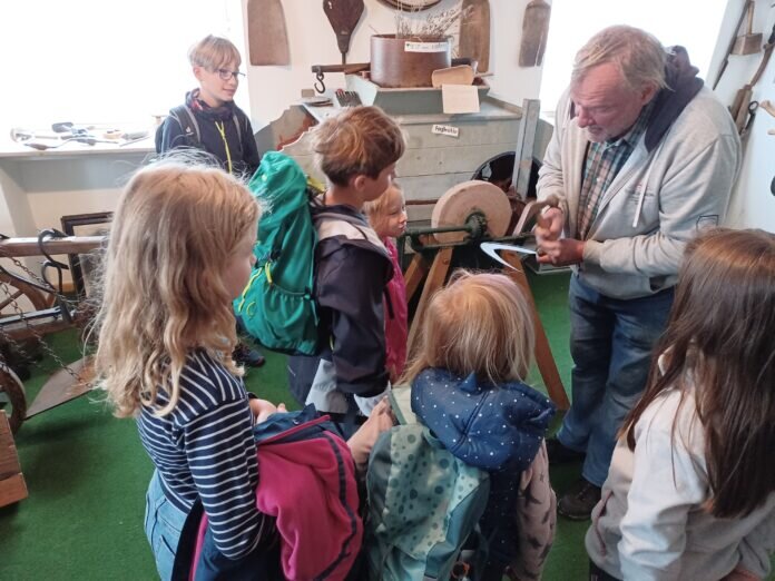 Klaus Bloch führt den Kindern das Dengeln vor